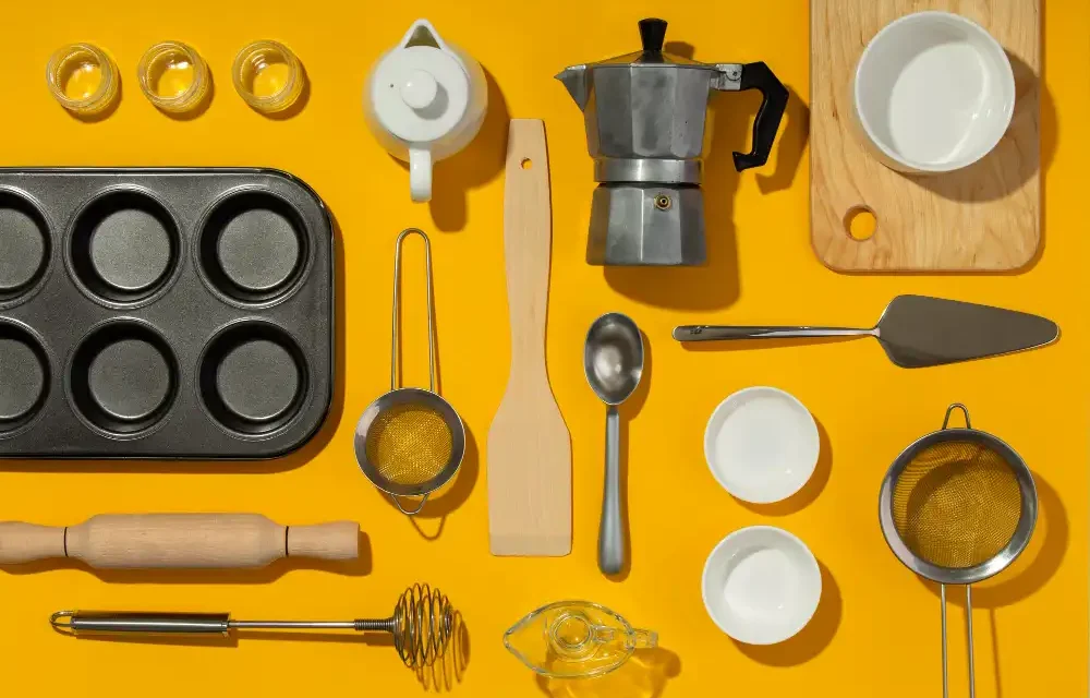 Variedades de utensílios essenciais para cozinhas modernas, incluindo formas para assar, colheres, espátulas, peneiras, e utensílios de medição, organizados sobre fundo amarelo.