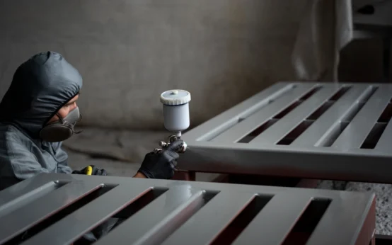 Profissional de pintura industrial aplicando tinta em grandes estruturas metálicas com equipamento especializado, ilustrando as movimentações do mercado de pintura industrial, tendências e oportunidades.