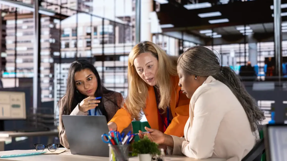 Três profissionais de empresas diferentes colaborando em uma reunião no escritório moderno, discutindo estratégias para desenvolver uma cultura de inovação empresarial.