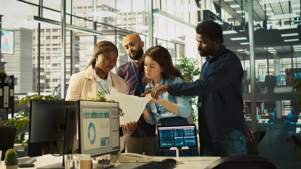 Profissionais de diferentes origens colaborando em um ambiente de escritório moderno com tecnologia avançada, promovendo inovação aberta por meio de parceria entre empresas e startups.