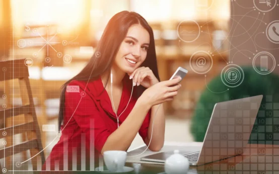 Como a IA Está Mudando a Rotina de Empresas e Consumidores: mulher em ambiente corporativo usando smartphone e laptop, com sobreposição de gráficos e ícones digitais de tecnologia ao fundo